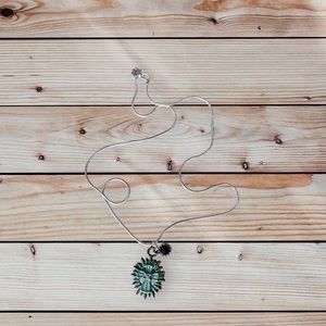 Teal cross with black charm necklace.